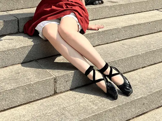 woman sitting on steps in red dress and square toe flats