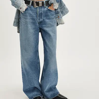 model wearing orange free people barrel jeans with brown boots