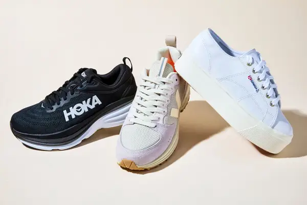 Three platform sneakers we recommend, including Hoka, Veja, and Superga, on a cream floor