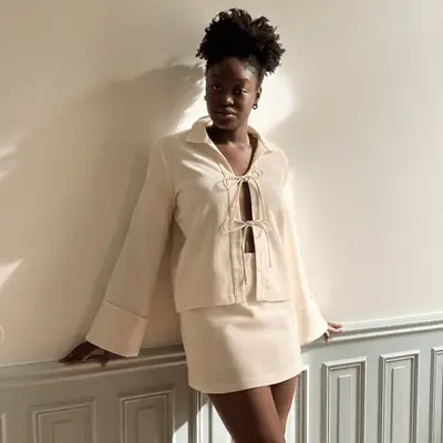 A woman wearing a white copenhagen blouse and a white skirt.