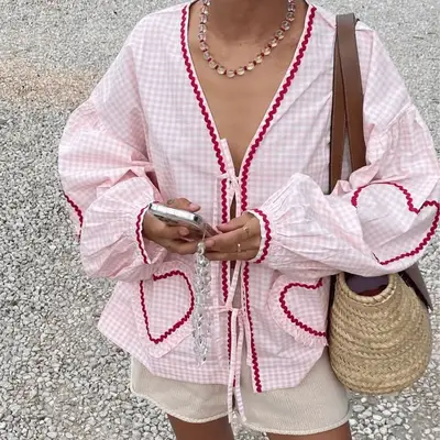 A woman wearing a pink gigham and heart Sissel Edelbo Copenhagen top.