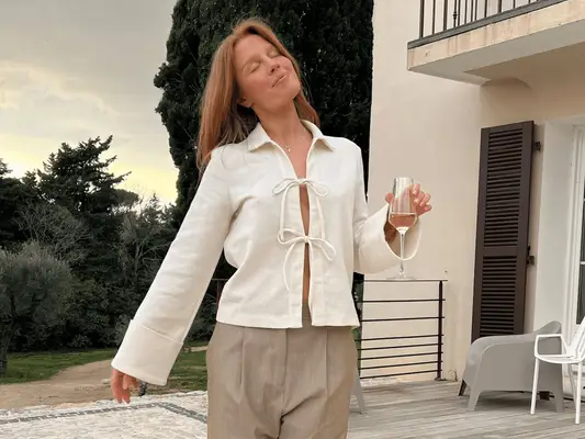 Close up of a model wearing a white tie up, long sleeve Copenhagen blouse.