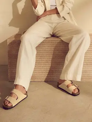 Birkenstock sandals and off-white linen wide leg pants and blazer on model