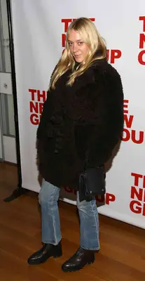 Chloe Sevigny wearing a faux fur black coat with straight leg blue jeans and black boots