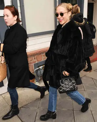Chloe Sevigny wearing a black faux fur coat with blue jeans and black boots