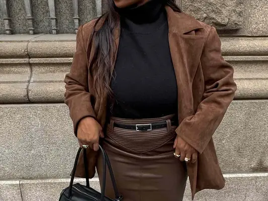 Nnenna Echem wears a brown suede jacket, black turtleneck, ad chocolate brown leather skirt