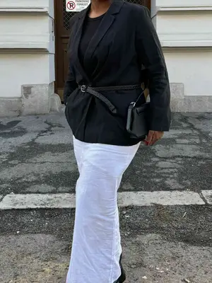 Nnenna Echem wears a black belted blazer, white skirt, black handbag