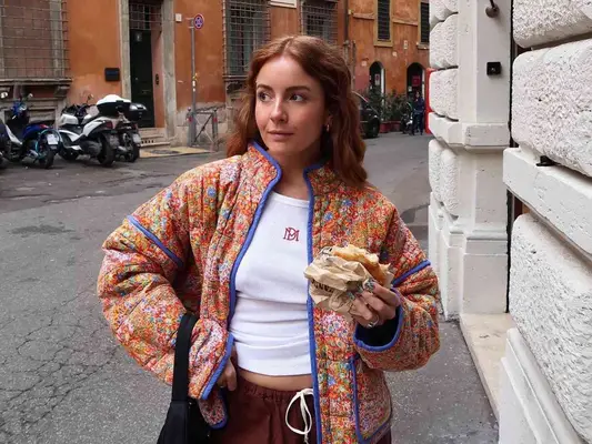 Woman wearing colorful quilted jacket and white ribbed tank top