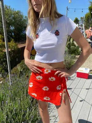 Model wearing a white tee with two ladybugs and a red wrap skort with daisies