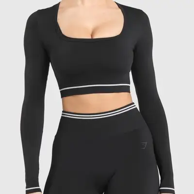 A model is wearing a black long sleeve crop top with white trim 