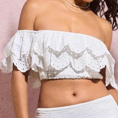 A model is wearing a white ruffled crop top 