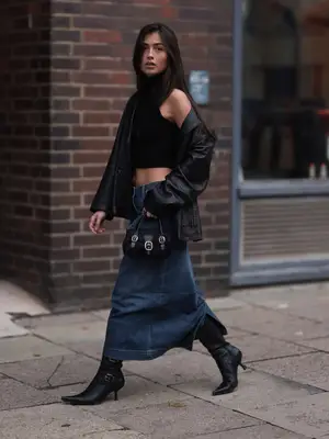 model wearing black jacket, long denim skirt, black kitten heel boots