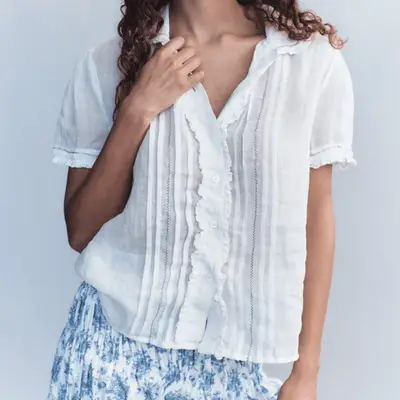 White New Balance Sneakers, Jean Shorts, Woman in White Ruffled Tops, Gold and Gemstone Bracelets