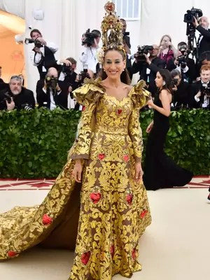 Sarah Jessica Parker at the Met Gala wearing a gold gown with red heart detailing and a structured gold headpiece