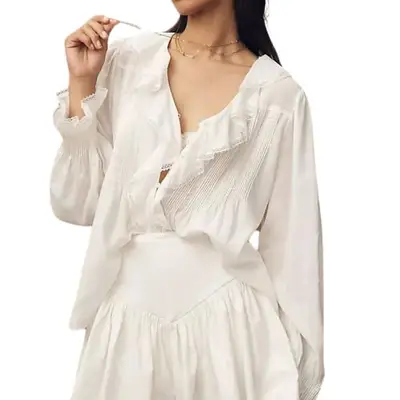 model wearing a ruffled white top with long sleeves