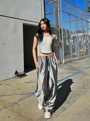 person wears silver track pants, a structured corset top, and sneakers