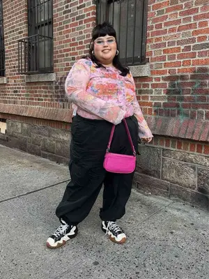 person wearing a floral mesh top, athletic pants, and sporty shoes. They
