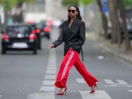 model wearing an oversized black blazer, red athletic pants, and red stiletto heels
