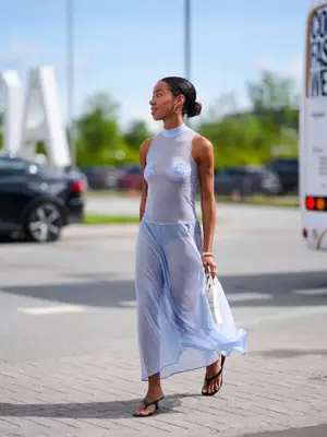 Woman wearing sheer blue dress and black heeled flip-flops