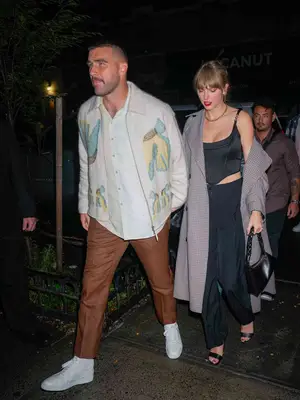 Taylor Swift wears a black corset top, tailored pants, plaid coat, and black Aupen handbag while leaving the SNL after party with Travis Kelce