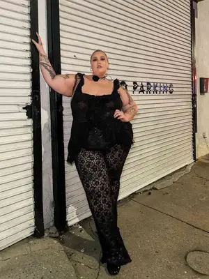 Abby Bible wears lace pants, a black tank top, and a rose choker