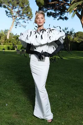 Elsa Hosk wears a white Nina Ricci gown with black feathers and gloves to the 2024 amfAR Cannes Gala