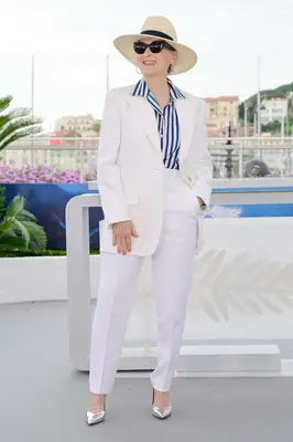 Meryl Streep wears a Michael Kors collection white suit with navy striped top, sunglasses, and sun hat to the 2024 Cannes Film Festival