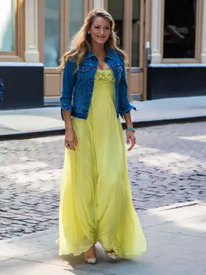 Blake Lively wears a denim jacket and yellow maxi dress with heels