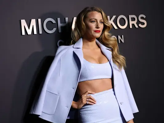 Blake Lively wears a periwinkle top, skirt, and jacket set to the Michael Kors Fall 2022 show