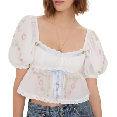 For Love & Lemons Carrington Blouse in white with embroidery and blue ribbon on model styled with pendant necklace and medium wash denim