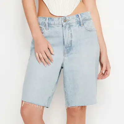 Good American Good 90s Bermuda Shorts in light wash indigo on model paired with white striped top