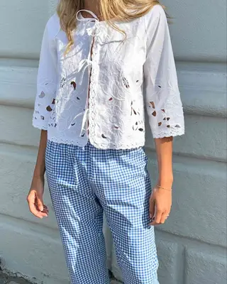 Close-up of woman wearing eyelet white front-tie blouse and blue gingham pants