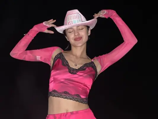 Olivia Rodrigo wears a hot pink lace crop top, slip skirt, and shrug with light pink birthday cowboy hat