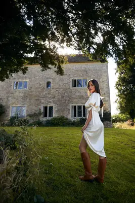 Kacey Musgraves wearing a silk dress and riding boots from her Reformation collection