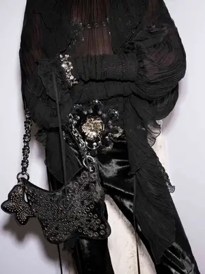 Close-up og black sheer puff-sleeve top, floral belt, and butterfly bag from Blumarine Fall 2025 collection