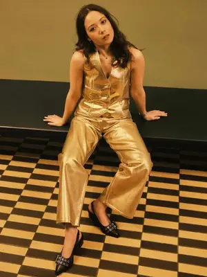 Laufey wears a gold vest, trousers, and black buckled slingback heels