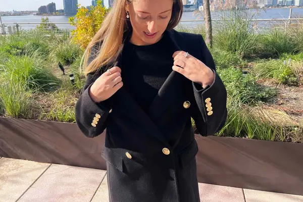 A person touching the collar of the Babaton The Constant Coat