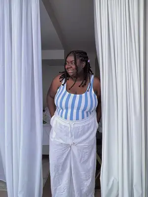 Abisola Omole wears a blue and white striped bodysuit and white linen pants