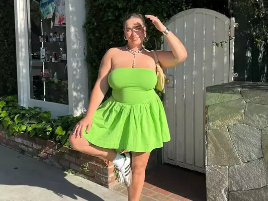 Julia Berit wears a lime green strapless mini dress, Adidas sneakers with socks, neutral handbag, and silver jewelry