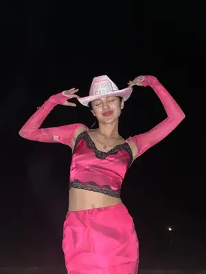Olivia Rodrigo wears a lace trim hot pink crop top, silky midi skirt, sheer bolero, and pink cowboy hat