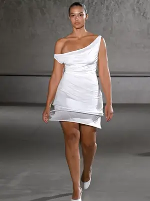 Model wears a white mini dress with asymmetrical straps on the Tory Burch spring 2024 runway