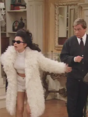 Fran Fine from The Nanny wearing black sunglasses, a white fur coat, white crop top, and white high-waisted shorts