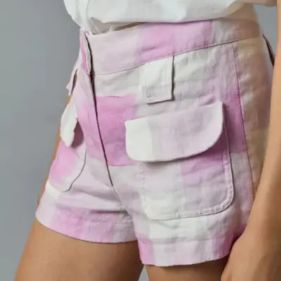 A model is wearing a pink and white plaid micro linen shorts with big pockets.