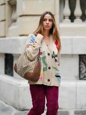 Nnenna Echem wearing a dark red sweater, charcoal a-line maxi skirt, a black belt, a pair of black Mary Janes, and a wine red handbag