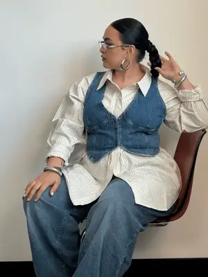 Woman wears denim outfit with button-down shirt under denim vest paired with jeans