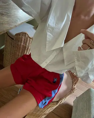 A woman wearing a blouse and athletic shorts. 