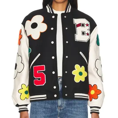model wearing black varsity jacket with cream sleeves and colorful patches all over