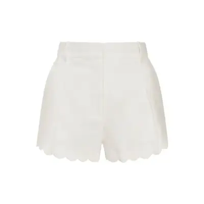 high waisted white shorts with scallop trim against plain background