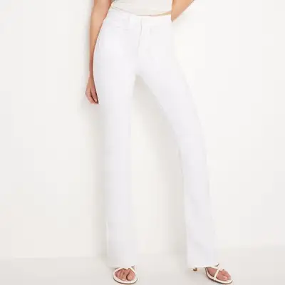 model wearing white bootcut jeans high waisted against plain background