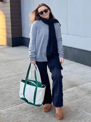 MYM Beauty editor Holly Rhue wearing a grey sweater, navy scarf, navy pants, and ugg boots.